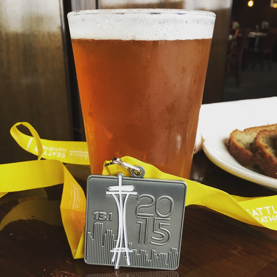 Medal from completing the Seattle half-marathon next to a glass of beer.