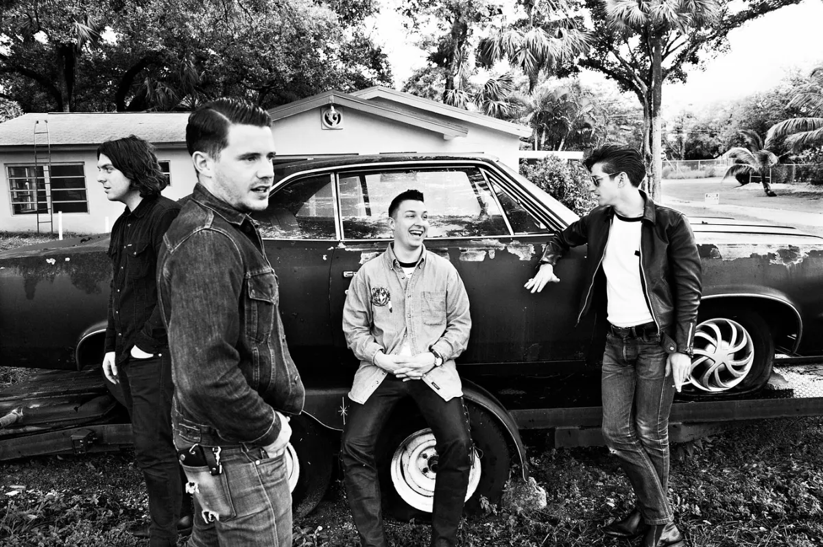 Arctic Monkeys band members hanging about around a car.